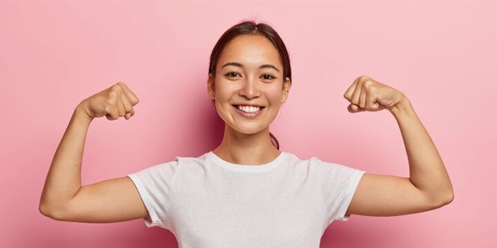woman flexing her arms in pink background